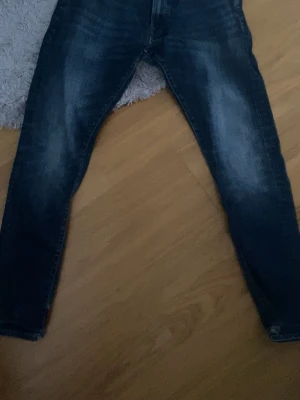 Mörkblå jeans från Polo Ralph Lauren - Pris går att diskuteras vid snabb affär !!!!!. Snygga mörkblå jeans från Polo Ralph Lauren med klassisk femficksmodell och gul kontrastsöm. Jeansen har en lätt tvättad look med slitningar på låren och raka ben. Perfekta för en avslappnad och trendig stil.