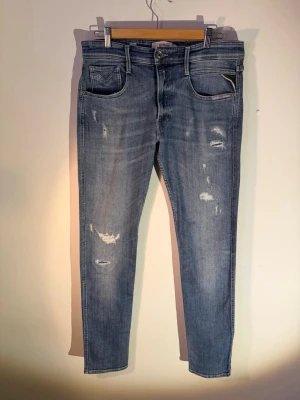 Replay Anbass - 1 Par blåa Replay Anbass med riktigt snygg tvätt och slitningar. Storlek 31/34 men funkar bra för 31/33 också. Jeansen är i superbra skick, nypris: 1499kr. Tveka inte på att höra av er om ni har några funderingar!