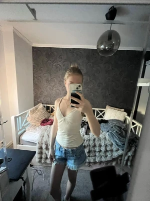 Vit o gul linnetopp från Brandy Melville - Supersöt vit linnetopp från Brandy Melville med smala axelband och lätt v-ringning. Toppen är figurnära och har en enkel, stilren design som passar perfekt till jeansshorts eller kjol. Tillverkad i mjuk bomull med lite stretch för extra komfort.
