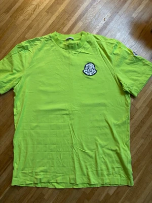 Gul Moncler t-shirt med logga - Snygg grön t-shirt från Moncler med en stor broderad logga på bröstet i vitt och svart. Klassisk rund halsringning och korta ärmar. Perfekt för dig som vill sticka ut med en färgstark och trendig look.
