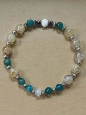 Elastiskt armband med färgade pärlor - Snyggt armband med elastisk tråd, dekorerat med runda pärlor i turkos, vit och beige samt små silverfärgade detaljer mellan pärlorna. Perfekt accessoar för att ge din outfit en färgklick och unik touch.