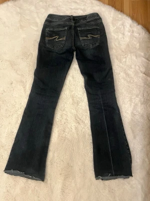 Mörkblå bootcut jeans vintage - Snygga mörkblå bootcut jeans från Silver Jeans Co, jeansen har snygga detaljer som gör de unika. Jag är 156 och de passar mig bra i längden! 