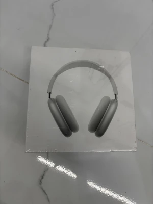 Apple AirPods Max silver - Snygga och moderna Apple AirPods Max i silver. Over-ear hörlurar med stilren design, mjuka öronkuddar och justerbart huvudband i metall och mesh. Perfekta för musik, gaming eller film med grym ljudkvalitet och ikonisk Apple-look.