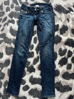 Mörkblåa True Religion jeans - Väldigt lågmidjade snygga mörkblåa jeans från True Religion, i en mer skinny/straight modell. Säljer då de tyvärr blivit för små för mig. Jeansen har storlek 23 och längden har funkat super för mig som är ca 162 cm lång☺️Köpte här på plick för ett bra tag sen så jeansen är absolut i använt skick men inga större defekter😁
