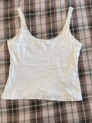 Vit spetslinnetopp från 157 - Säljer ett vitt linne från 157 med tunna axelband och spetsdetaljer längs kanterna!