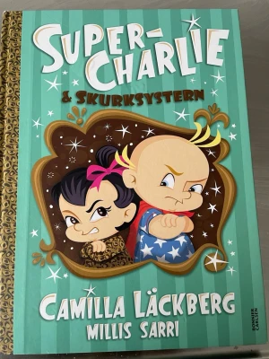 Super-Charlie & Skurksystern - Rolig och färgstark barnbok med tecknade illustrationer på omslaget. Boken har en turkos och brun framsida med vita och gula detaljer, och titeln är skriven i stora bokstäver. Författare är Camilla Läckberg och Millis Sarti.   Stor bok ca 30 cm lång och ca 22 cm bred 