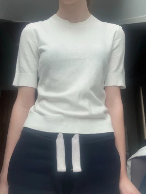 Vit topp med kort ärm - Vit kortärmad topp. Det syns inte så bra men den är lite genomskinlig. Använd väldigt mycket, men inget som syns så mycket, mer än att den är lite skrynklig på grund av att den tvättats många gånger. 