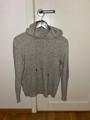 Kaschmir Hoodie - Mysig grå hoodie från Massimo Dutti med justerbar huva och långa ärmar. Tillverkad i mjukt material som känns skönt mot huden. Perfekt för chill dagar och enkel att matcha med jeans eller mjukisbyxor.