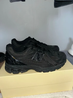 Svarta New Balance sneakers - Säljer ett par helsvarta New Balance sneakers med mesh och syntetmaterial. Storlek 43 helt i nyskick. Skorna har klassisk låg profil, robust sula och snygga detaljer med New Balance-loggan på sidan. Perfekta för dig som vill ha en clean och sportig look.