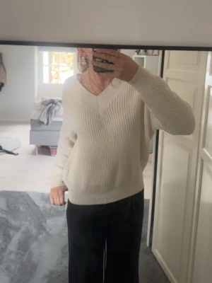 Krämvit stickad tröja med v-ringning - Säljer en krämvit stickad tröja med bred v-ringning och ribbad struktur. Från märket amisu, i nyskick
