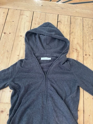 Mörkgrå zip hoodie från Sail racing - Mysig mörkgrå hoodie från Sail racing med dragkedja framtill och stor huva. Tillverkad i mjukt material som känns skönt mot huden. Perfekt för en avslappnad och chill stil. Långa ärmar och enkel design utan tryck eller mönster. Storleken är M men är som S