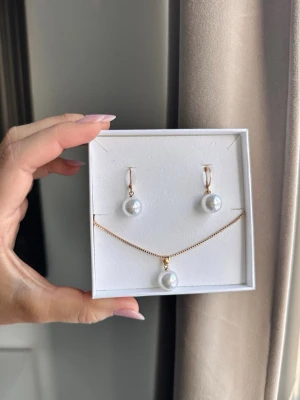 Guldhalsband med vit pärla - Nytt elegant halsband med matchande örhängen i guldton. Både halsbandet och örhängena har stora vita pärlor som hängsmycke. (Kommer utan box)🤍