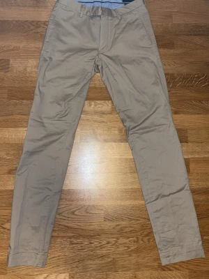 Beige chinos med rak passform - Snygga beige chinos med rak passform och klassisk design. Byxorna har sidofickor fram och två bakfickor med knapp. Tillverkade i ett mjukt och lätt bomullsmaterial som ger en skön känsla. Perfekta för dig som gillar stilrena och enkla plagg. Ordinarie pris: 2000 kr