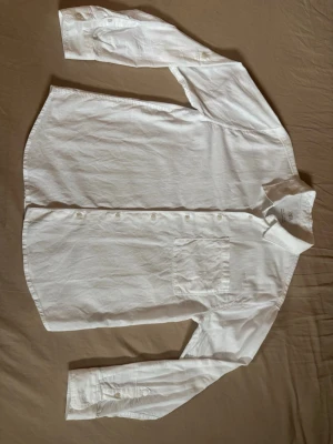 Vit linneskjorta från Zara - Klassisk vit skjorta från Zara i linne med lång ärm och bröstficka. Skjortan har knappar framtill och vid ärmsluten, perfekt för en clean och stilren look. Enkel att matcha med det mesta och riktigt skön på sommaren.