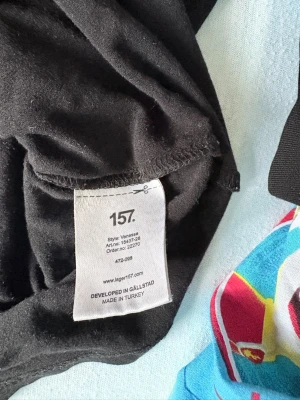 Svart långärmad topp från 157 - En svart långärmad topp från 157 med rundad, djup ringning. Tillverkad i mjuk bomull som känns skön mot huden. Perfekt basplagg 