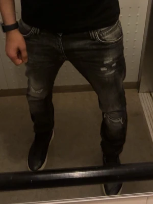 Jack & Jones slim fit jeans, med slitningar  - Snygga svarta slim-fit jeans från Jack & Jones modell Glenn. Jeansen har slitna detaljer, tvättad look. Storlek 32/32