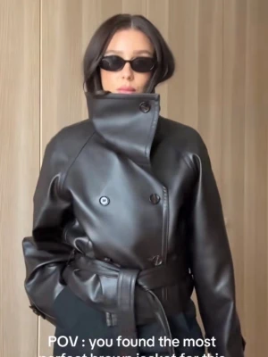 Virala mango jackan  - Snygg brun skinnjacka från mango med bred krage, dubbelknäppning och bälte i midjan. Jackan har en cool, boxig passform och detaljer vid ärmsluten. Perfekt för dig som vill ha en trendig och stilren look.