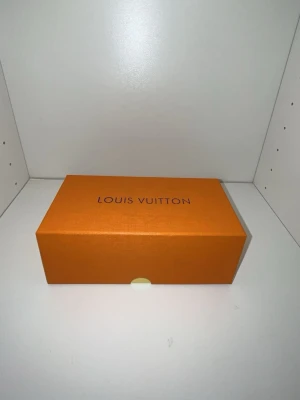 Louis Vuitton solglasögon - Säljer en exklusiv solglasögon från Louis Vuitton. Fodralet kommer i en elegant mörkblå färg med präglad logotyp och levereras i en klassisk orange Louis Vuitton-box. Perfekt för att förvara och skydda dina solglasögon med stil.