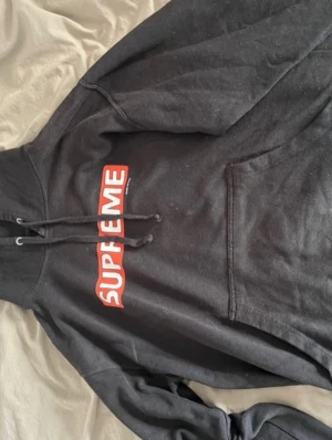 Svart Supreme x Powell Peralta hoodie med logga - Säljer en svart hoodie från Supreme och Powell Peralta med den klassiska röda boxloggan på bröstet. Hoodien har huva med dragsko och en stor magficka framtill. Tillverkad i mjuk bomullsblandning som är skön att bära. Perfekt för dig som gillar streetwear och vill sticka ut.