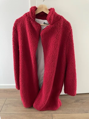 Röd teddykappa från SHEIN  - Mysig röd teddyjacka från Shein med öppen framsida utan knäppning. Jackan har en fluffig, mjuk struktur.