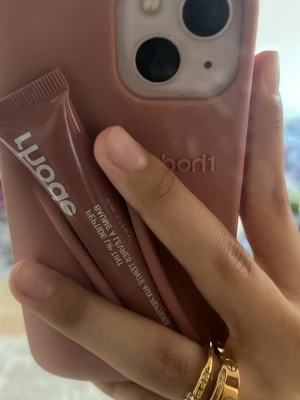 Rosa mobilskal från rhode - Säljer ett snyggt rosa mobilskal från rhode som har en stilren och matt finish. Skalet är gjort i ett mjukt silikonmaterial och har en smart hållare för läppbalsam på baksidan. Perfekt för dig som vill ha både skydd och funktion i ett.