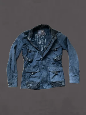 Mörkblå fieldjacket från G-Star RAW - Mörkblå fieldjacket från G-Star RAW med fyra stora fickor framtill, hög krage med knappdetaljer och dragkedja. Jackan har svarta detaljer på axlar och fickor samt justerbara ärmslut. Tillverkad i slitstarkt material och har en cool, urban look.