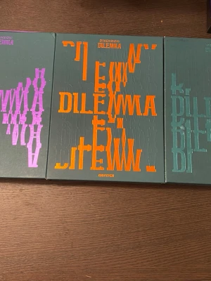 DIMENSION : DILEMMA bokset ENHYPEN - Säljer ett bokset med tre böcker från ENHYPENs DIMENSION : DILEMMA-serie. Omslagen är mörkgröna med grafiska tryck i lila, orange och turkos. Perfekt för dig som gillar snygg design och samlarobjekt inom skönlitteratur. 2 albums har inga photocards och vissa saker fattas