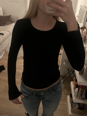 Tajt svart trlja - En fin,tajt, svart tröja med slits vid ärmarna.