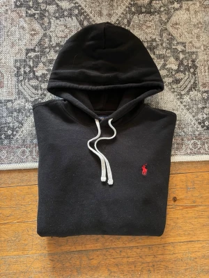 Svart Ralph Lauren Hoodie-Röd Pony - Hej!👋 Säljer en svart hoodie med röd pony-logga från polo Ralph Lauren. Hoodien är i utmärkt skick och har inga hål eller fläckar! Storlek S herr, 170/92A. Hör gärna av er om ni har några frågor!💯😀