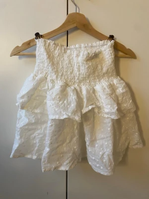 vit detaljerad volang kjol - en vit volang kjol med små detaljer i tyget, riktigt söt till sommaren med typ en topp eller med en stickad beige tröja!! knappt använd så riktigt bra skick!