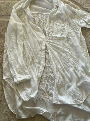 Vit skjorta från KappAhl i bomull - Klassisk vit skjorta från KappAhl i mjuk bomull. Skjortan har lång ärm, bröstficka och knappar framtill. Perfekt oversized look och lätt att styla till olika outfits.