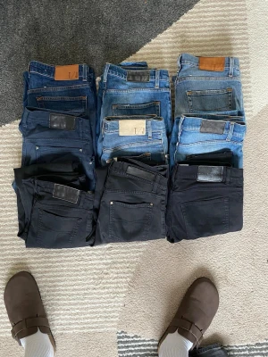 Mix av blå och svarta jeans  - Säljer ett gäng jeans i olika blå och svarta nyanser. Klassisk femficksmodell, raka och smala ben. Några har läderpatch på linningen. Perfekta för dig som vill ha flera stilar att välja mellan. Materialet är denim, vissa par ser ut att vara stretch.9x bulk TT jeans 