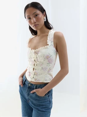 Blommig korsettopp med spetsdetaljer - Romantisk korsettopp i ljus ton med blommigt mönster i pastellfärger. Toppen har snörning framtill, spetskant vid urringningen och breda axelband. Figurnära och croppad passform, perfekt för sommarens alla looks.