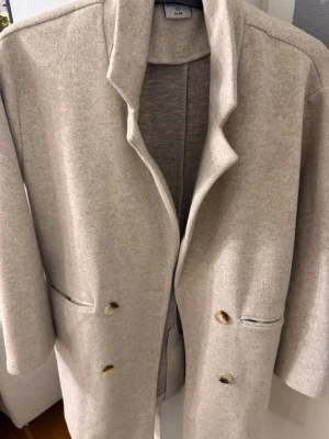 Beige ullkappa med knappar - Beige kappa från Stories