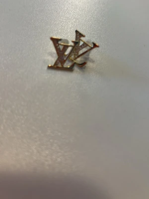 Guldörhänge med stenar - Säljer ett stilrent örhänge i guldfärg med LV-logga. 