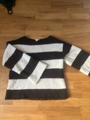 Randig stickad tröja Gina Tricot - Stickad tröja från Gina Tricot med breda svarta och vita ränder. Tröjan har en rak passform, rund halsringning och vida ärmar. Perfekt för en avslappnad och trendig look. Materialet är mjukt och mysigt.