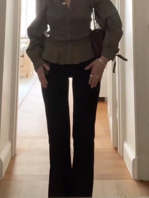 Svarta utsvängda kostymbyxor - Snygga svarta kostymbyxor med utsvängda ben och hög midja. Byxorna har en klassisk passform och är tillverkade i ett mjukt, vävt material som ger en stilren look. Perfekta att matcha med en blus. Bikbok ganska säker på att de är i modell Vera har inte haft på mig dem ALLS därför säljer jag jag är 167cm med långa ben o dem är jätte bra i längden 