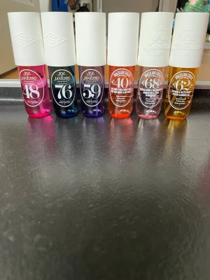 Sol de Janeiro parfym mist set - Säljer ett färgglatt set med Sol de Janeiro parfym mist i olika dofter och färger. Flaskorna är i plast med vita, rosa, gröna och röda lock. Dofterna inkluderar bl.a. 48, 76, 59, 40, 68, 62, Flor Mistica, Beijos de Sol, Summer e Amor och Carioca crush. Knappt använda! Säljes som paket.