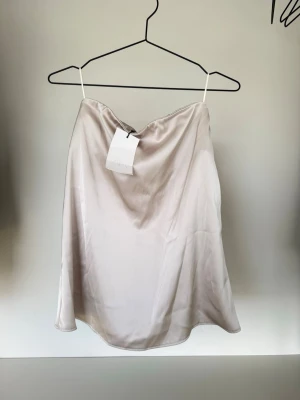 Zara topp - Snygg axelbandslös tubtopp i champagnefärgad satin. Storlek XS men passar även S, prislapp kvar. 