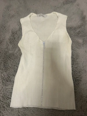 Vit topp - En superfin vit topp med en dragkedja som har kristaller på. Det står att den är i storlek L men hade sagt att den är storlek M. Den är endast testad, aldrig använd och är från Skovhuus!🤍