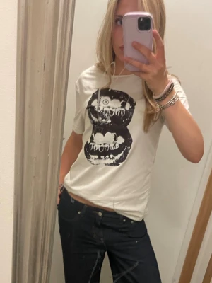 Vit t-shirt med svart tryck - Vit t-shirt med ett stort svart tryck av två läppar . T-shirten har rund halsringning och korta ärmar. Perfekt för en avslappnad och cool stil. Jag köpte den begagnat för 70kr men jag tror ursprungligen den är från SHEIN 