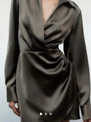 Olivgrön omlottklänning i satin - Snygg olivgrön kort omlottklänning från NA-KD i glansigt satinmaterial. Klänningen har lång ärm, krage och djup v-ringning. Sitter snyggt med draperad effekt i midjan och ger en elegant look.