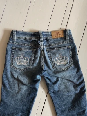 Lågmidjade jeans - Coola bootcut lågmidjade jeans från märket Fuerwei Jeanswear! Den översta knappen är lite lös därav billigare pris och slitningar på innerlåren, Midjemått 38 cm, innerbenslängd 81cm