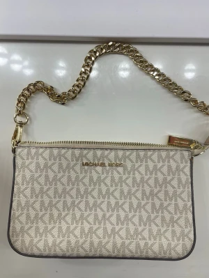 Beige kuvertväska Michael Kors - Snygg beige kuvertväska från Michael Kors med guldfärgad kedja och dragkedja. Använd få par gånger. Perfekt att bära i handen eller över axeln för en trendig look nu inför sommaren. Pris kan diskuteras.