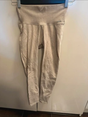 Beige ribbade leggings och topp från Aim'n - Säljer ett par beige ribbade leggings från Aim'n med hög midja och stretchigt material. De har en snygg, diskret logga på linningen och är perfekta för en avslappnad och trendig look. Passar till både träning och chill. Det kommer även en matchande topp till - aimn perfekt för dig som är aktiv och tränar nu under sommaren då det är en så härlig färg!🥰 byxorna är i storlek xs och toppen är i s men passar även en xs då den är väldigt tajt.  OBS: FRAKTAR INOM 24H!🩷