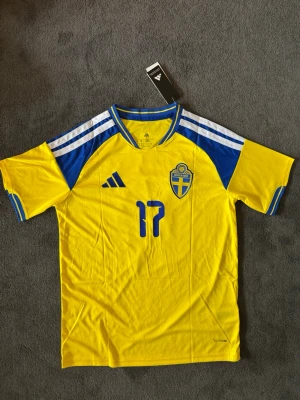Sverige VM 26/27 hemma Gyökeres - Fotbollströja med Gyökeres på ryggen. Tröjan är helt ny med tagg kvar och i perfekt skick. Perfekt för dig som är supporter, samlar på fotbollströjor eller vill ha en snygg tröja till träning och vardag.                                                                      🟡 Skickas inom 24 timmar.                                         Vid intresse eller frågor är det bara att skicka 👍