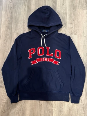 Polo Ralph Lauren Hoodie Mörkblå Strl S - Polo Ralph Lauren mörkblå hoodie med klassisk passform och stilren design som funkar till allt, storlek S, axelbredd 50 cm, bröstvidd 50 cm, midja 42 cm, armlängd 60 cm, längd 64 cm, i fint skick.