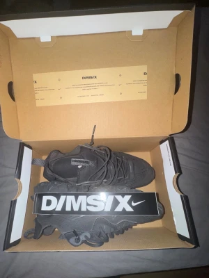 Nike D/MS/X svarta sneakers - Säljer ett par helsvarta Nike D/MS/X sneakers med chunky sula och coola detaljer. Skorna har mesh och syntetmaterial i ovandelen, samt en unik vågig sula som ger en modern vibe. Perfekta för dig som gillar streetwear och vill sticka ut.