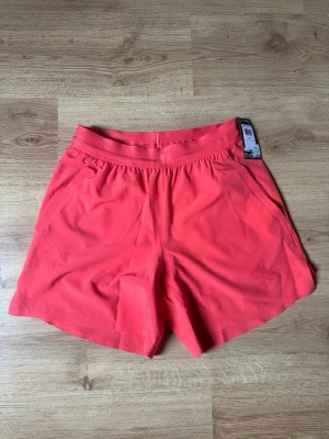 Under Armour shorts - Snygga rosa shorts från Under Armour med loose passform och elastisk midja. Shortsen har fickor på sidorna och är tillverkade i ett lätt och bekvämt material perfekt inför sommaren. Köpt nya för 749kr, säljer pga för liten storlek. Helt nya och oanvända.