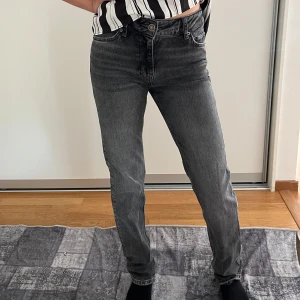 Grå raka jeans med medelhög midja från Zara - Säljer ett par grå jeans med klassisk femficksmodell och raka ben. Jeansen har medelhög midja och en snygg tvättad finish. Perfekta till sneakers eller boots och passar till  nästan allt i garderoben.